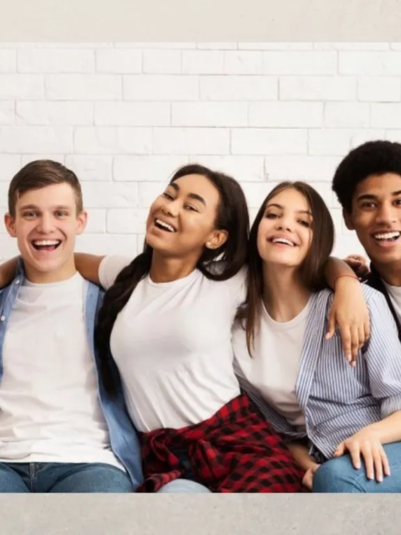 A Level age students sat together arm in arm, smiling.
