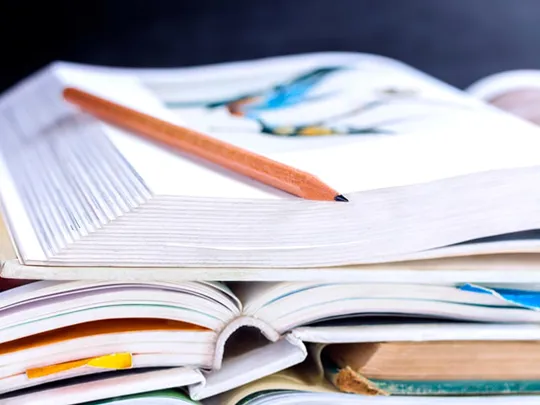 A pencil resting on some open school books.