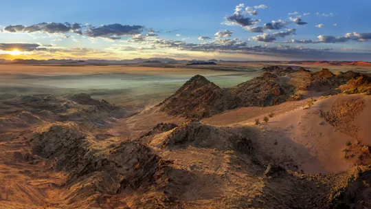 Expansive desert landscape in Namibia at sunset with rocky ridges and open plains