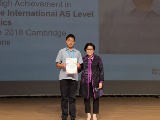 Wolsey Hall Oxford student Victor stands with his mother after being awarded Outstanding Cambridge Learner Award.