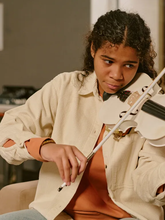 Focused teen practising the violin in a warm indoor space