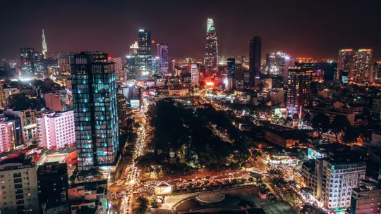 Vibrant aerial night view of Ho Chi Minh City lit with neon and high-rise buildings