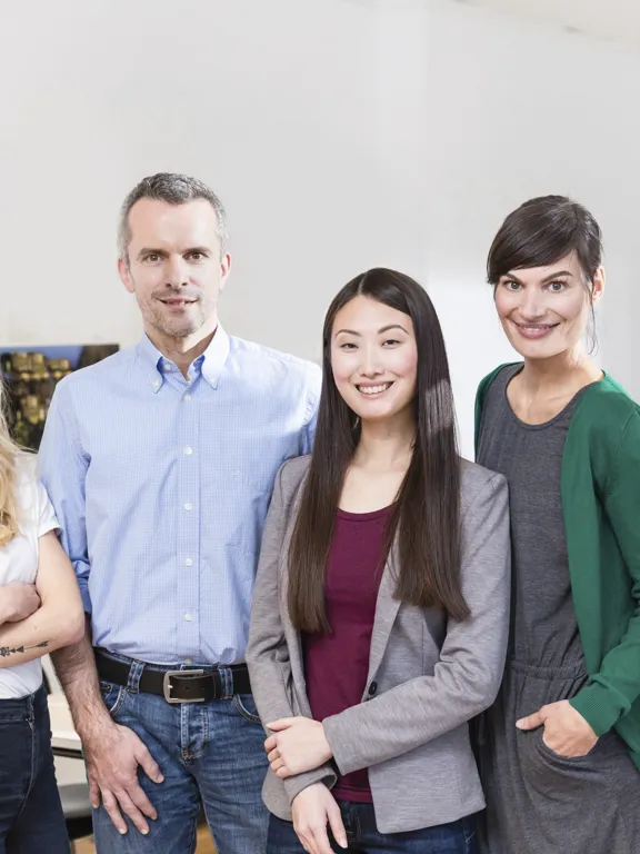 Diverse team of six professionals posing together in a well-lit office space.