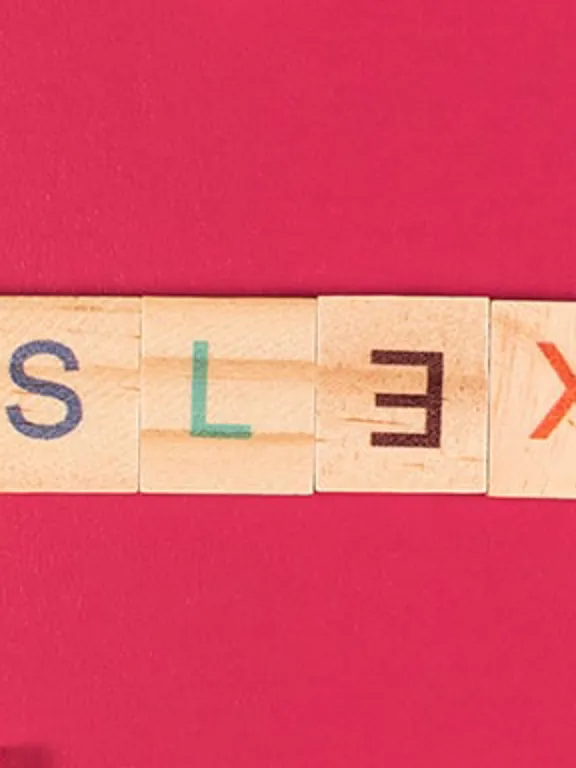 The word 'dyslexia' spelled out using wooden tiles, with the 'E' backwards to highlight the difficulty spelling for people who have dyslexia.