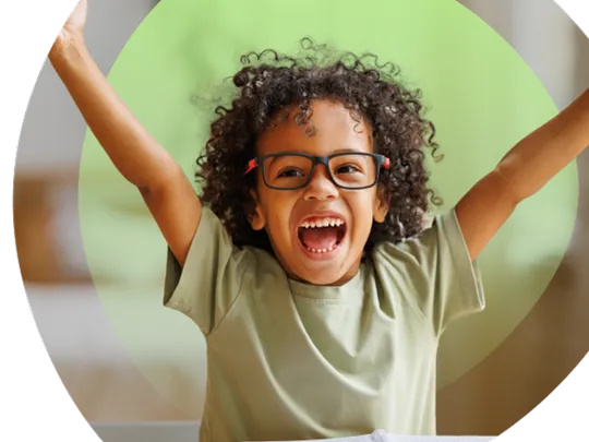 A photograph of a Primary-age student with curly hair and glasses looking excited with his hands in the air, within a green Wolsey Hall Oxford branded circle frame.