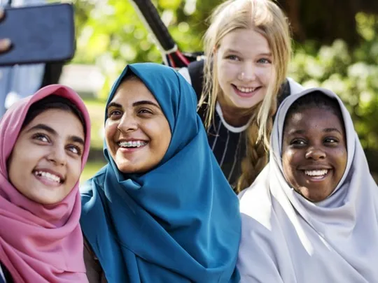 Highlighting the vibrant social life of homeschoolers in Sharjah: teenage friends taking a happy selfie together.