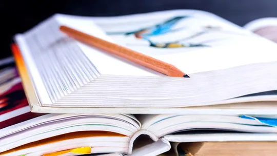 A pile of open text and note books in varying size.