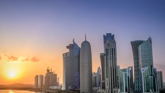 Doha skyline at sunset with iconic modern towers and a golden sky over the bay