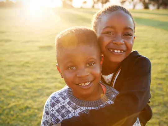 Smiling siblings enjoying a sunny day outside, illustrating the positive social and emotional aspects of homeschooling in Johannesburg.