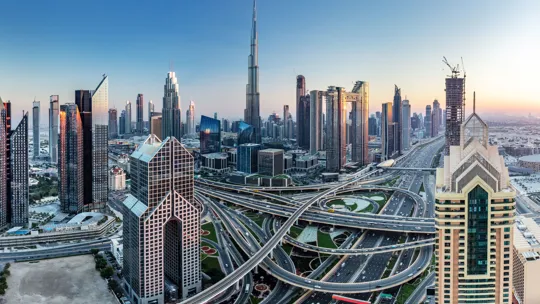 Modern skyline of Dubai with Burj Khalifa and network of motorways at sunrise