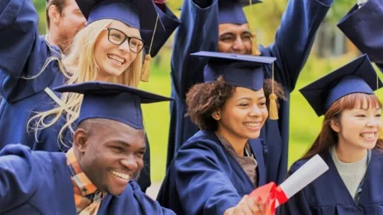 A variety of university students getting ready to graduate wearing gowns and hats.