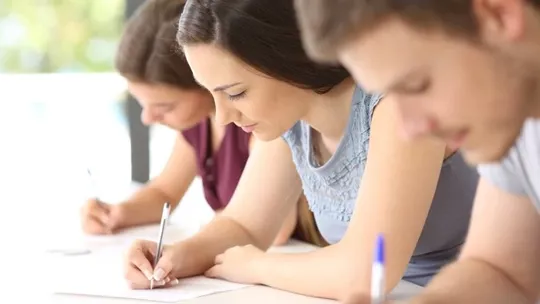 Three A Level students making notes on what they're studying.