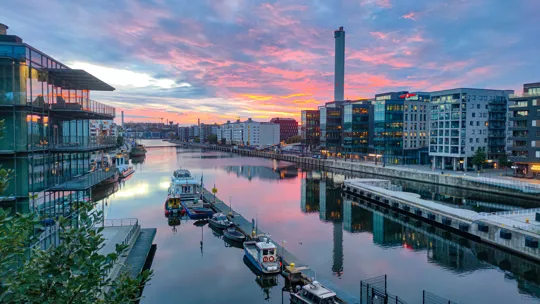 Modern waterfront buildings and boats along the Liffey River in Dublin at sunset
