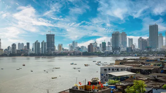 Mumbai skyline with high-rise buildings across the water and small fishing boats in the foreground