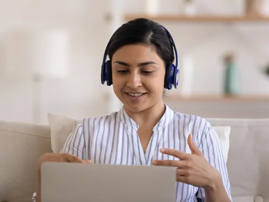 Student participating in online tuition session from home in Durban, wearing headphones and engaging with her laptop.