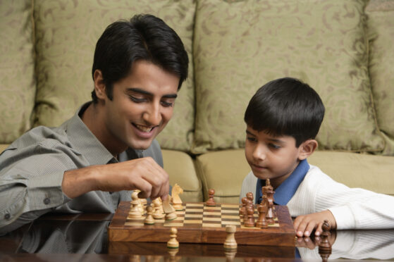 homeschooling gifted child playing chess with his dad